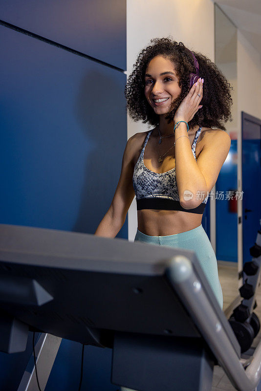 Curly-haired young woman on a treadmill looking contented